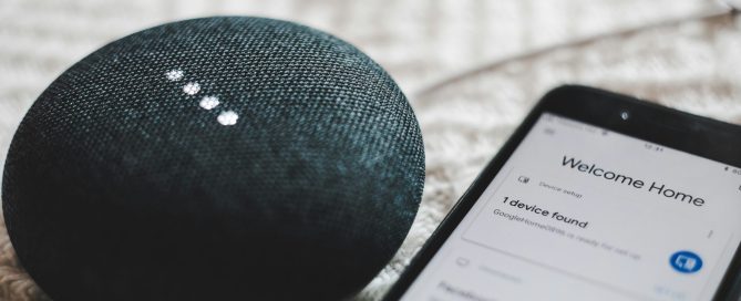 Turned-on charcoal Google Home Mini and smartphone photo