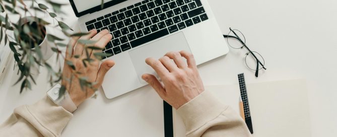 Free An overhead view of a person working on a laptop in a minimalist home office setting. Stock Photo