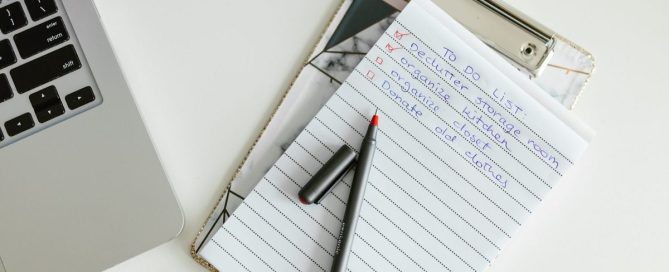 IT checklist on a clipboard next to a laptop on an office desk