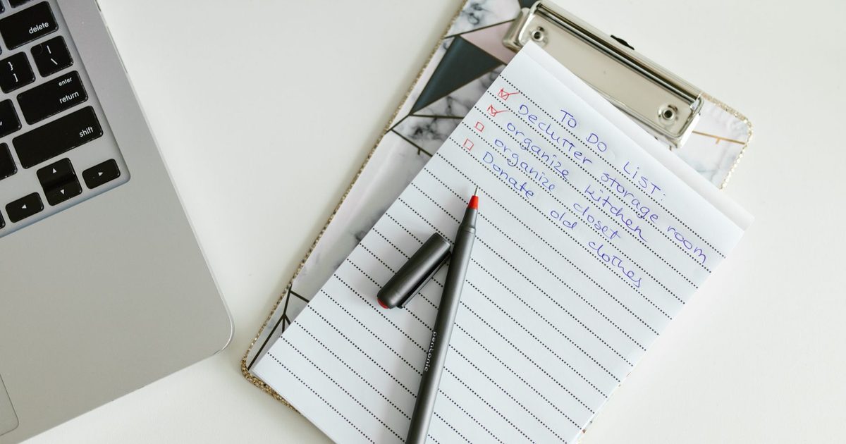 IT checklist on a clipboard next to a laptop on an office desk