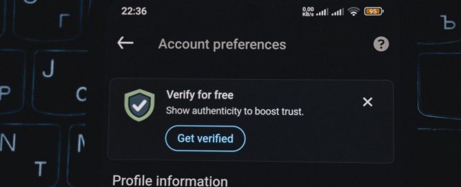 Phone showing a login verification code in front of a laptop