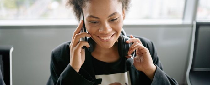 Modern office desk phone beside a laptop and headset